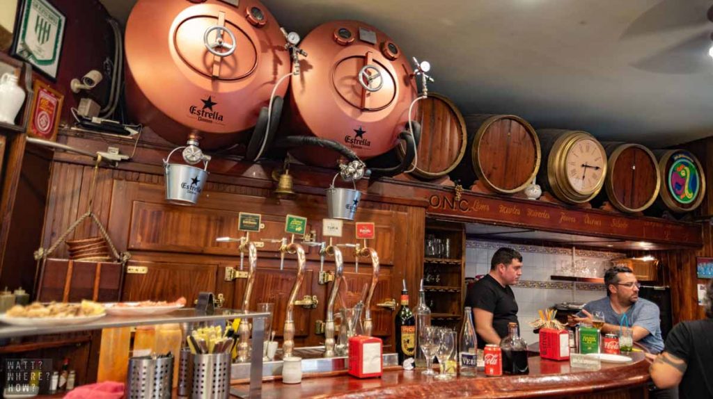 Bar Jai Ca is an old wood-paneled bar with large copper Estrella kegs adding charm to the cramped space. 